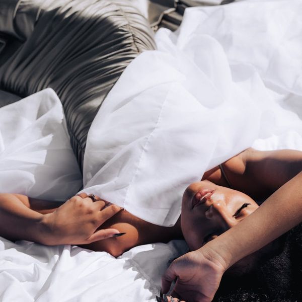 Woman in a peaceful yoga pose against a dark teal background.